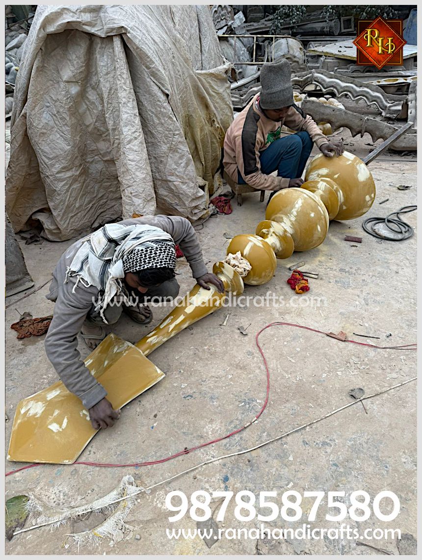 Artisans meticulously finishing a large, 6-foot golden Kalash spire with a smooth metallic luster in a workshop setting.