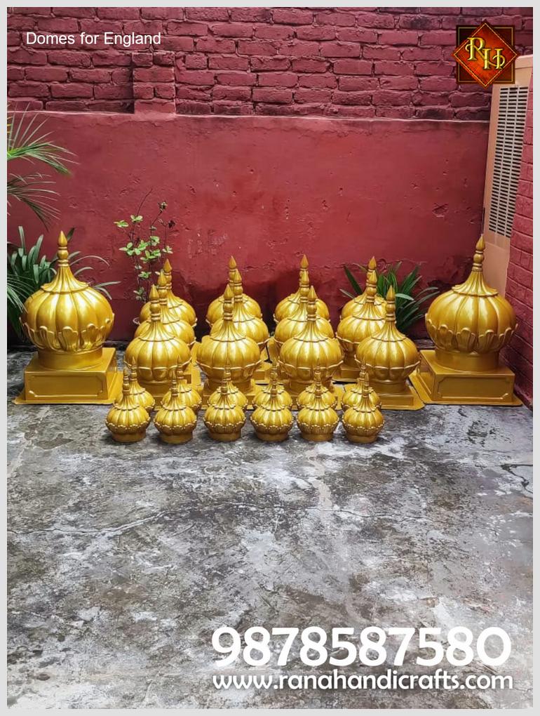 A collection of golden-coloured Gurdwara Sahib domes in various sizes, manufactured by Rana Handicrafts International for export to the UK, neatly arranged outdoors with contact number 9878587580 displayed at the bottom.