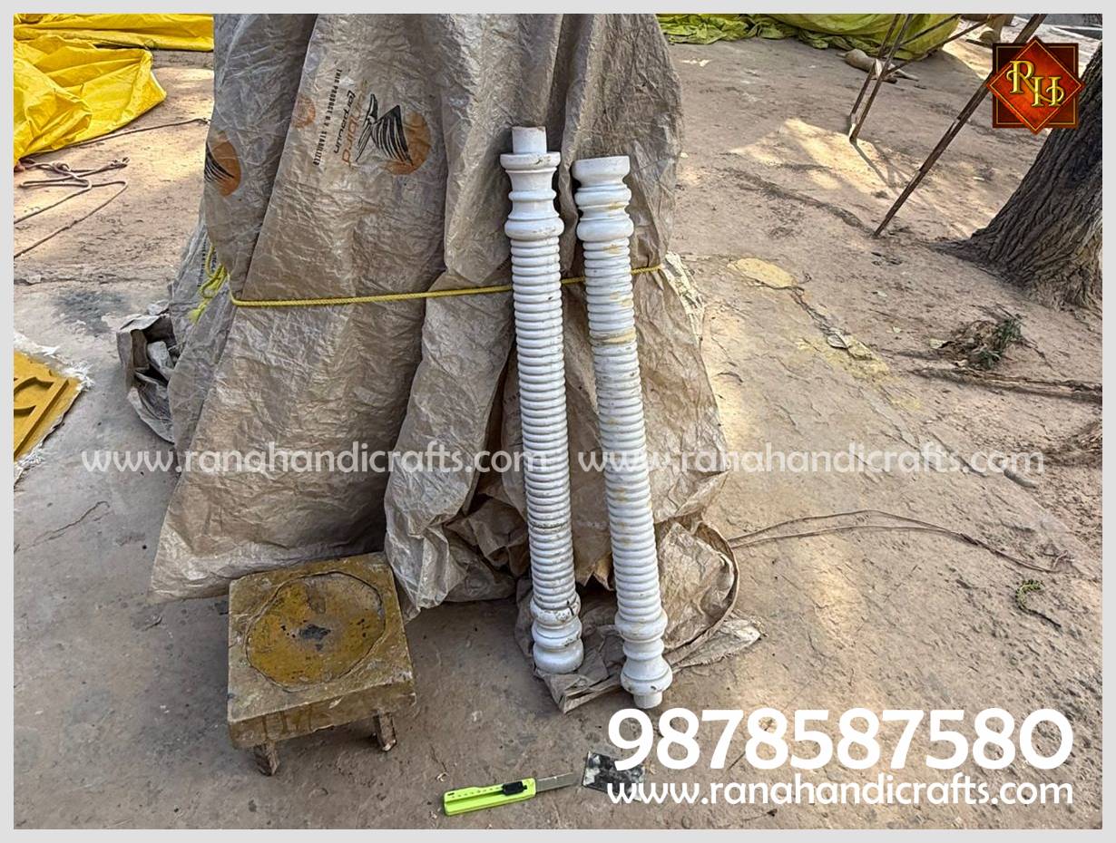 Two intricately carved white pillars for the HM-03 Palki Sahib standing against a support.