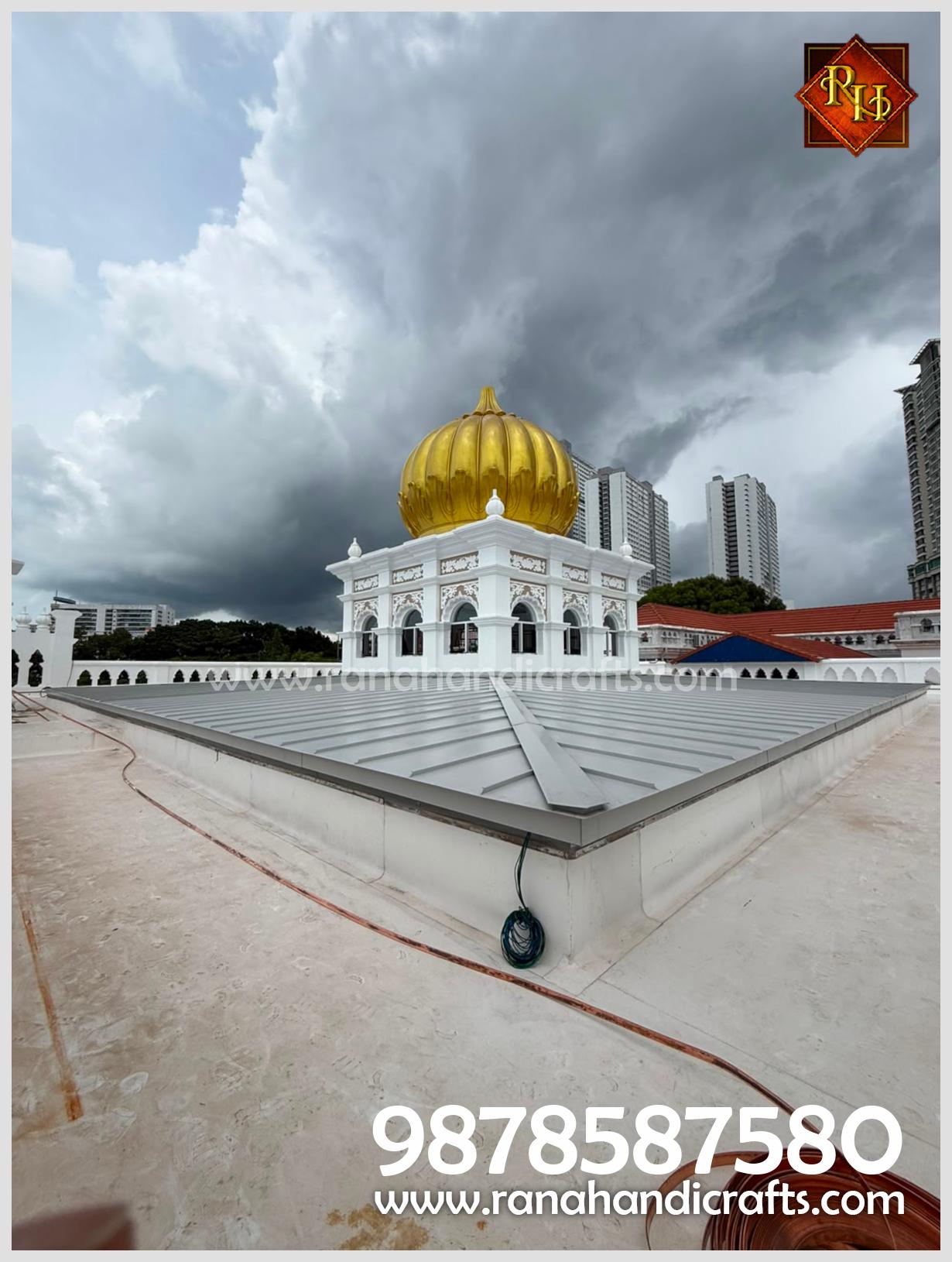 A large 20-foot diameter golden gurdwara dome installed at Wadda Gurdwara Sahib Penang, featuring a white structure with intricate detailing, manufactured by Rana Handicrafts International.